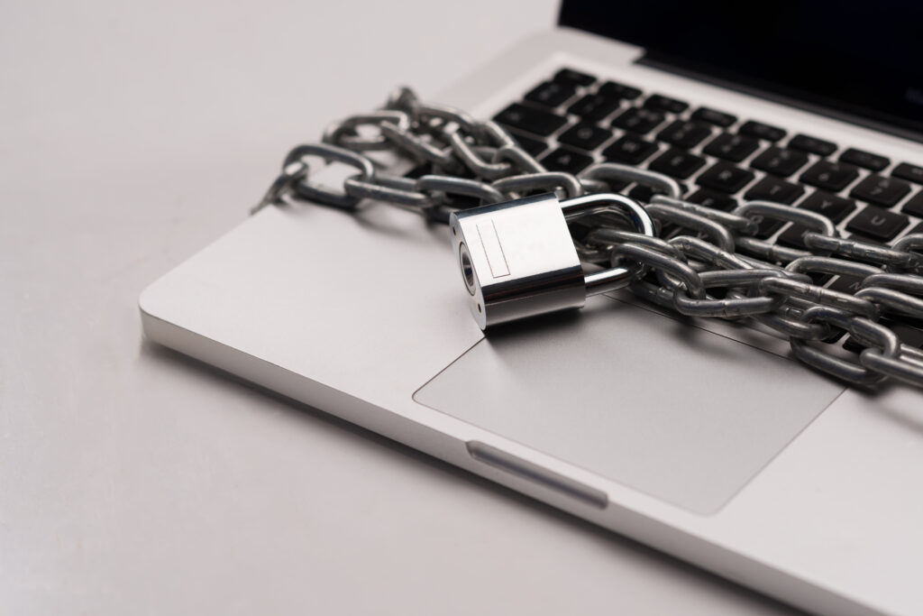 A laptop wrapped in chains with a padlock, symbolising the ransomware recovery process and the importance of strengthening IT security and monitoring systems after recovery.